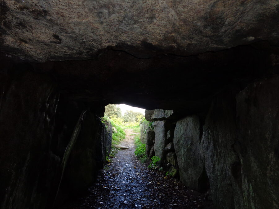 Dimly lit passage constructed from large boulders. This is Le Creux ès Faies passage tomb: a well preserved megalithic passage tomb dating from between 3,000 and 2,500 BC. The tomb is located on a small headland to the north of L'Eree Bay on Guernsey's west coast. In local folklore the passage is known as the entrance to the Fairy Kingdom. It was thought that fairies came out at midnight on moonlit nights to dance on the Mont Saint and Le Catioroc.