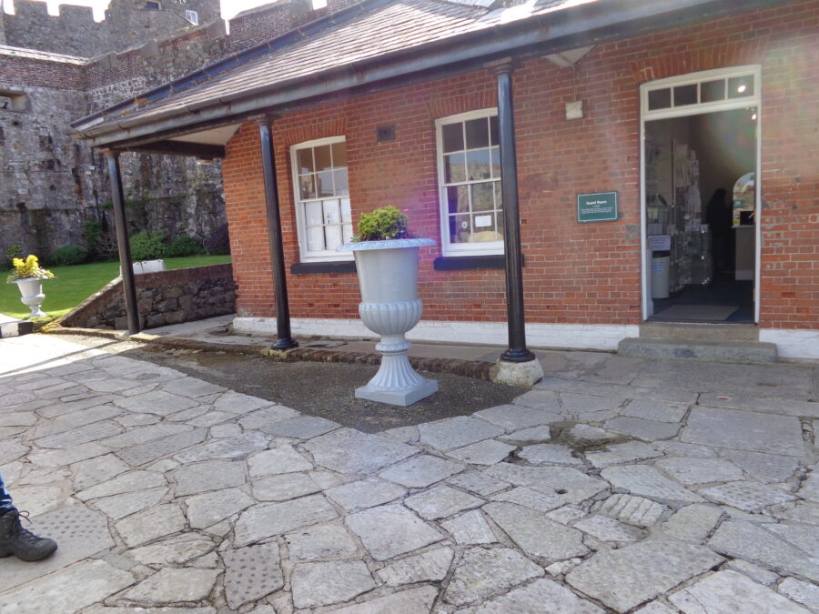The red brick building in front was originally the Guard Room built around 1850. It is today the castle's ticket office and shop. This is located in the Outer Ward. The tiled roof of the Guard Room has a wide overhang and is supported by metal pillars. 