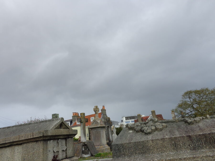 View across Candie Cemetery which opened in 1830. Two stone tombs can be seen in the foreground with various grave stones and monuments behind.