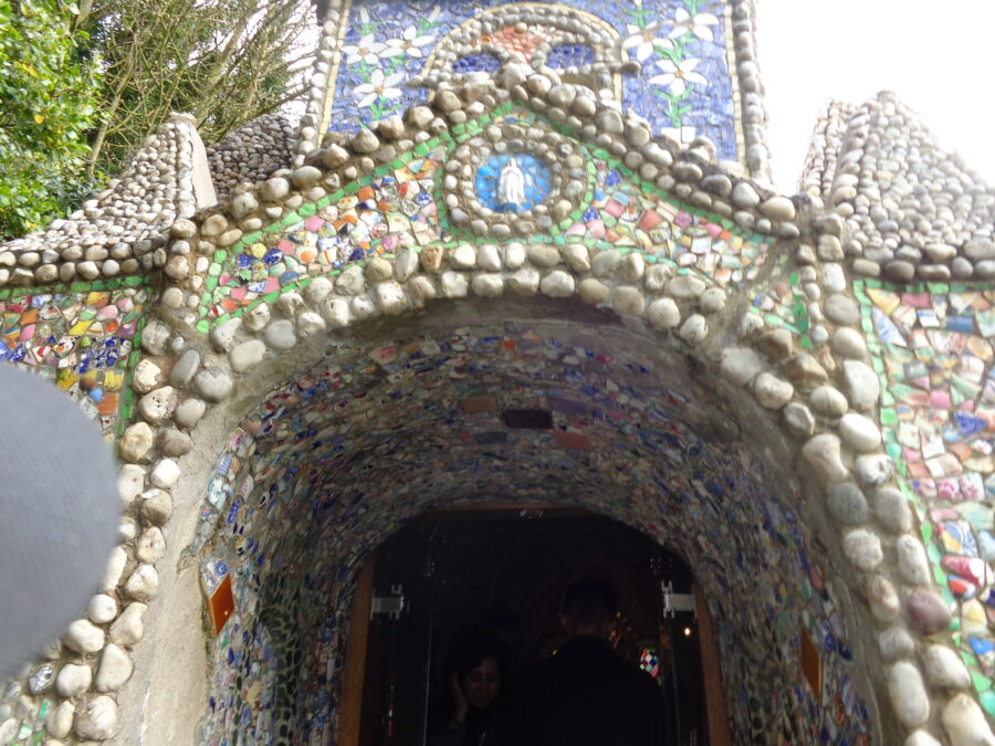Now outside the Little Chapel looking towards the doorway. The exterior walls are again decorated with a mosaic of broken pottery as well as pebbles. The Virgin Mary is depicted above the doorway and the mosaic decoration depicts flowers on the chapel's small tower above.