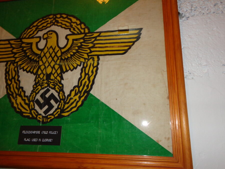 A flag used in Guernsey by the German Field Police (Feldgendarmerie) during the World War Two occupation. The flag is split diagonally into two white and two green triangles. In the centre is a large eagle and swastika emblem.  During World War Two the Channel Islands were under German military occupation from 30th June 1940 to 9th May 1945.