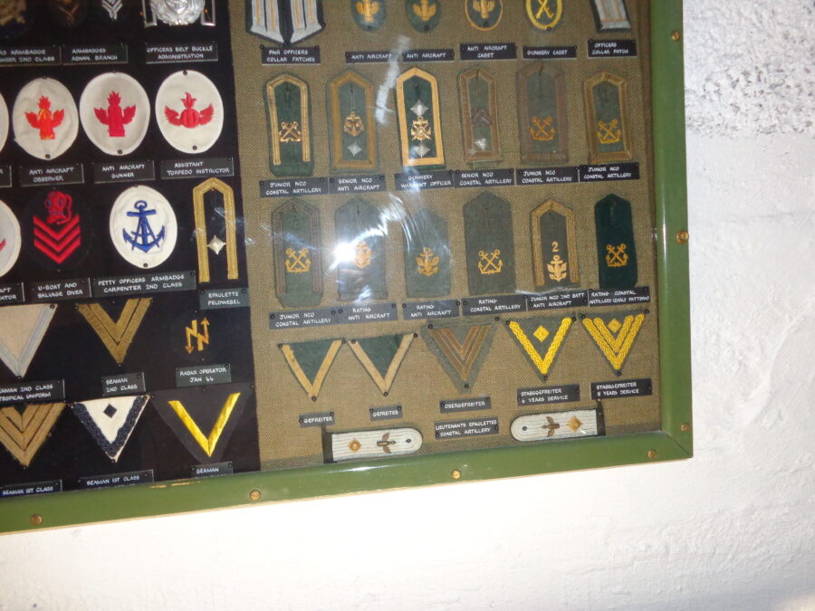 A glass display case containing a collection of German military epaulettes and badges dating from around the World War Two occupation of the Channel Islands.
