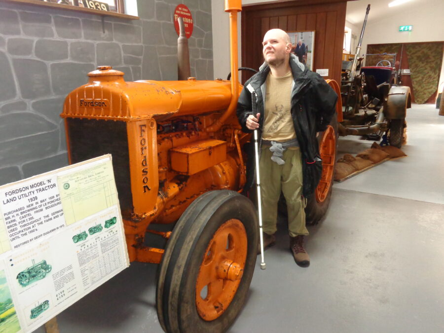 Tony standing by another orange Fordson tractor. According to the information board this is a Model 'N' land utility tractor purchased in 1939 for £205 and used at a local farm through the German occupation and on until the 1950s.