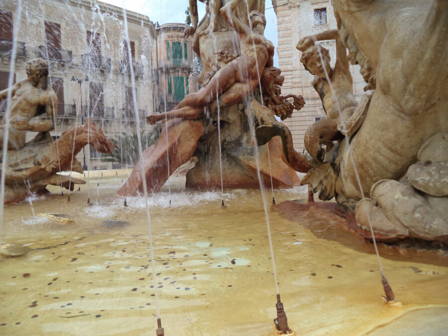 The Fountain of Diana in the centre of Piazza Archimede. This large fountain was designed by Giulio Moschetti in 1907. It pays homage to the goddess Diana (Artemis in Greek mythology). She is goddess of the countryside and nature, hunters, wildlife, childbirth, crossroads, the night, and the Moon. Diana is depicted atop a pedestrial in the centre of the fountain: only the pedestal is visible in this photo. Around Diana various other mythical figures are depicted with some of them riding on horses or sea monsters. These other figures include Arethusa and Alpheus. To the right a Triton can be seen riding a sea horse.