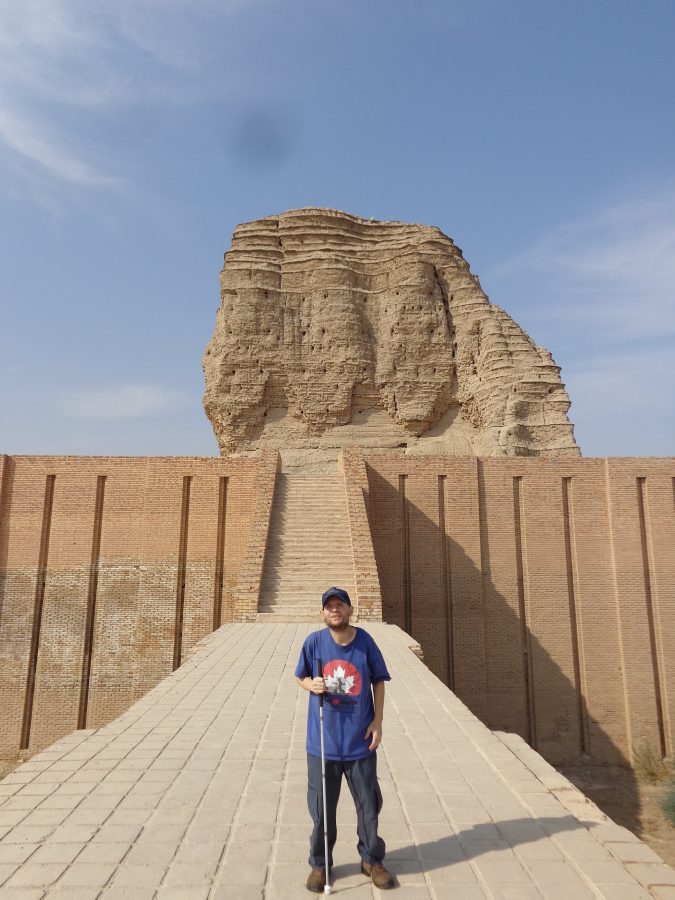 Tony on the raised walkway leading up to the Ziggurat's first level. The surface is paved with stone and a flight of brick steps can be seen ahead. The massive towering central part of the Ziggurat, today heavily eroded, can be seen away above.