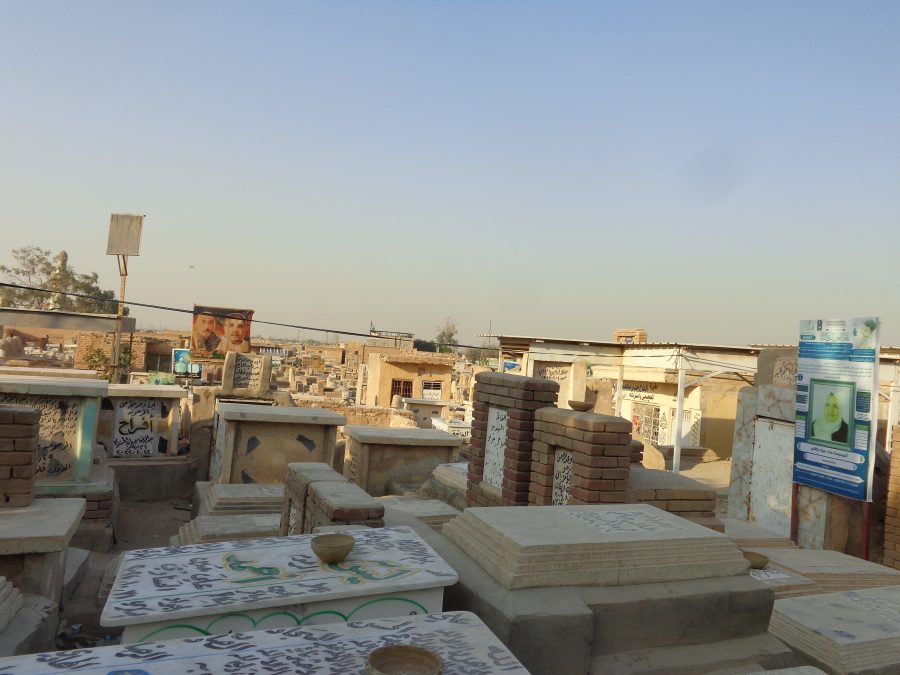 Another view of Wadi-us-Salaam cemetery. The tombs extend off into the distance ahead. Some of the graves in the foreground have bowls placed on top. These are likely filled with water.