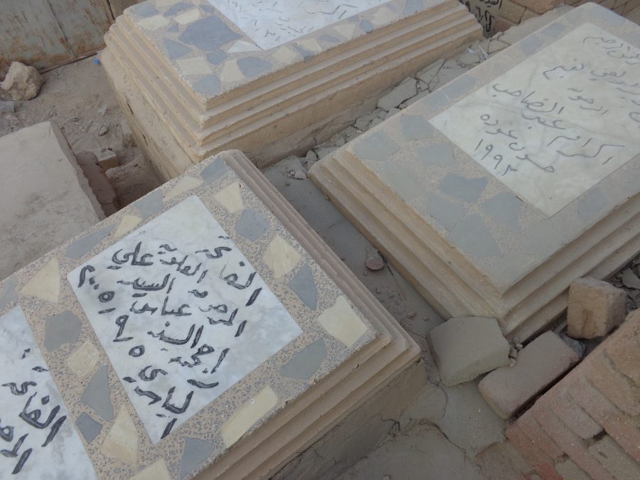 Close-up view of three tombs with inscriptions in black writing on top.