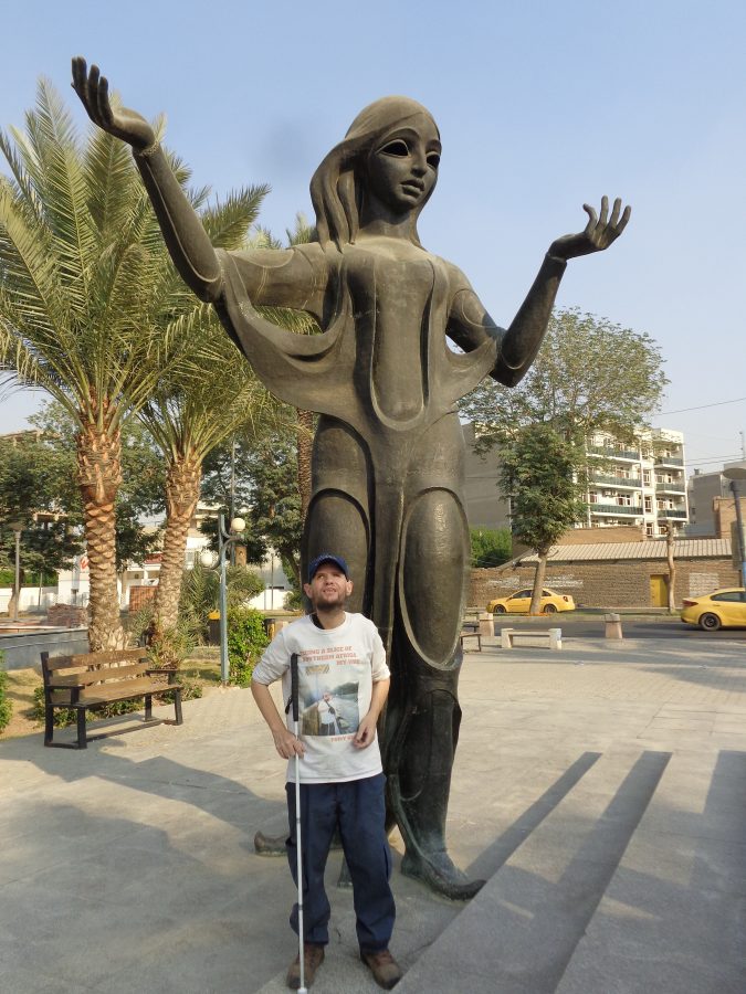 Tony stood in front of a large bronze statue of a woman with raised arms. This is Queen Scheherazade, the heroine from One Thousand and One Nights, a collection of Middle Eastern folktales compiled in the Arabic language during the Islamic Golden Age. The statue depicts Queen Scheherazade narrating a story to her reclining husband King Shahryar. Scheherazade volunteered to wed the murderous King Shahryar, who would take a different bride to bed each night, and have them executed before the following dawn. Scheherazade devised an ingenious plan to stave off her execution. Each night she would relate a story that enthralled the King, but she failed to reveal the story's climax until dawn, thus delaying her execution. This goes on for one thousand and one nights, hence the name. The statue was sculpted by Mohammed Ghani Hikmat in 1971 and is located on the Abu Nawas Corniche alongside the river Tigris.