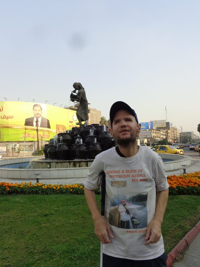 Tony stood in front of the Kahramana fountain and sculpture located in Kahramana Square on Al-Sa'adoon Street. The sculpture depicts a scene from the legend of Ali Baba and the Forty Thieves - a story taken from One Thousand and One Nights - in which the slave girl Morgiana outwitted a group of thieves by tricking them into hiding inside jars over which she poured hot oil. The fountain's base is circular. In the centre Morgiana is depicted standing on top of a stack of large jars. She is depicting holding a jug. Water can be seen pouring from the jug and also bubbling up from the jars. The water then flows down into a large pool around the base of the fountain. The fountain is 3.3 metres in height. It was officially opened in 1971 and is the work of the Iraqi sculptor, Mohammed Ghani Hikmat.